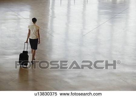 Woman walking with wheeled suitcase, elevated back view. View Large Photo Image Stock Photography - Woman walking with wheeled suitcase, elevated back view.. Fotosearch