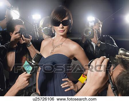 Woman wearing sunglasses posing on red carpet, being photographed by paparazzi View Large Photo Image Stock Photograph - Woman wearing sunglasses posing on red carpet, being photographed by paparazzi. Fotosearch