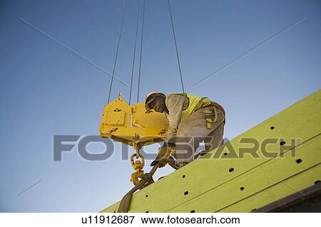 Workman fixes harness of hook block to building material View Large Photo Image Stock Photo - Workman fixes harness of hook block to building material. Fotosearch