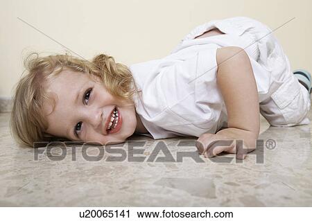 Stock Image - Young child lying on floor laughing. Fotosearch