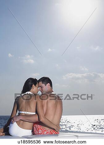 Young couple embracing on cushions on yacht, back view View Large Photo Image Stock Photograph - Young couple embracing on cushions on yacht, back view. Fotosearch