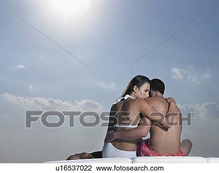 Young couple embracing on cushions outdoors, back view View Large Photo Image Stock Image - Young couple embracing on cushions outdoors, back view. Fotosearch
