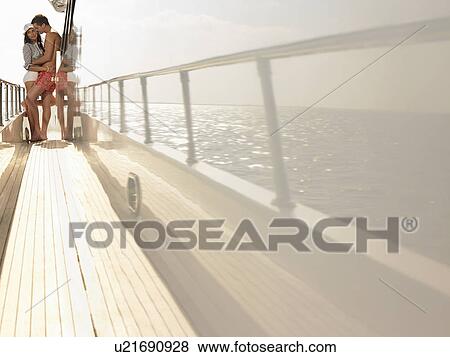 Stock Photo - Young couple embracing on yacht, side view. Fotosearch