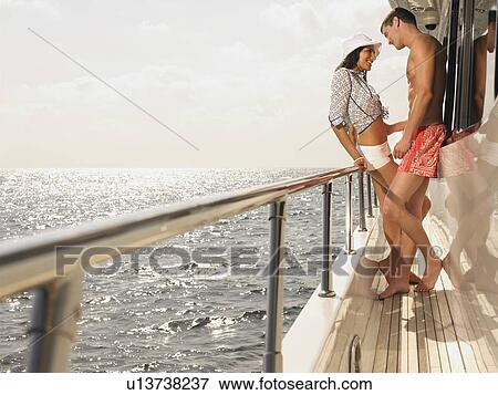 Young couple flirting on yacht, side view View Large Photo Image Stock Photo - Young couple flirting on yacht, side view. Fotosearch