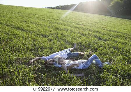 Stock Photo - Young Couple Lying in Empty Field. Fotosearch