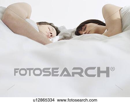 Young couple sleeping in bed, close-up View Large Photo Image Picture - Young couple sleeping in bed, close-up. Fotosearch
