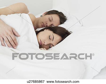 Young couple sleeping in bed, man's arm around woman View Large Photo Image Stock Photo - Young couple sleeping in bed, man's arm around woman. Fotosearch