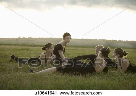Stock Image - Young dancers lie in a field talking. Fotosearch
