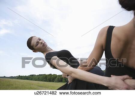 Stock Image - Young dancers support each other and lean backwards. Fotosearch