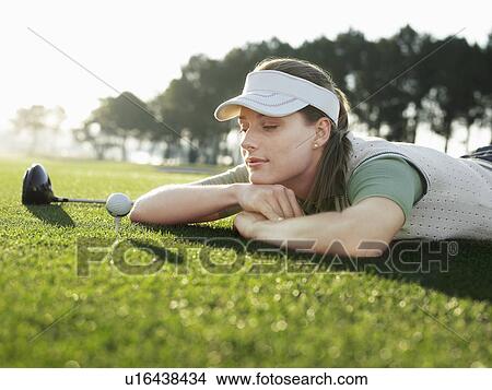 Young female golfer lying on court, looking at ball on tee View Large Photo Image Picture - Young female golfer lying on court, looking at ball on tee. Fotosearch