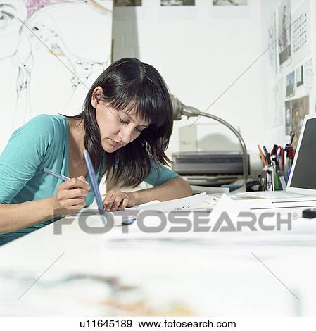 Stock Photo - Young female illustrator working in home office. Fotosearch