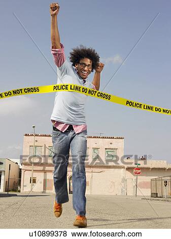 Stock Photo - Young man crossing police tape in street. Fotosearch