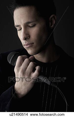 Young man holding microphone, close-up View Large Photo Image Picture - Young man holding microphone, close-up. Fotosearch