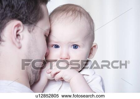 Stock Photography - Young man holding son looking at camera. Fotosearch