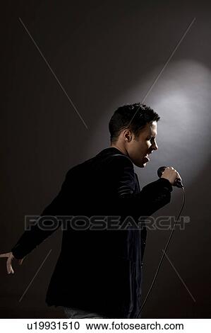 Stock Image - Young man singing in studio. Fotosearch