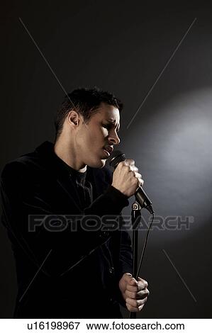 Stock Photo - Young man singing in studio. Fotosearch
