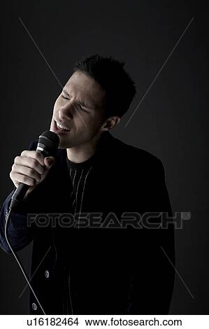 Picture - Young man singing into microphone. Fotosearch