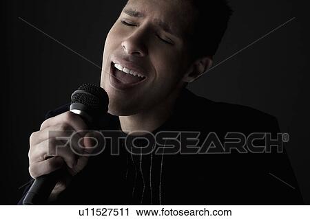 Young man singing into microphone, close-up View Large Photo Image Stock Image - Young man singing into microphone, close-up. Fotosearch