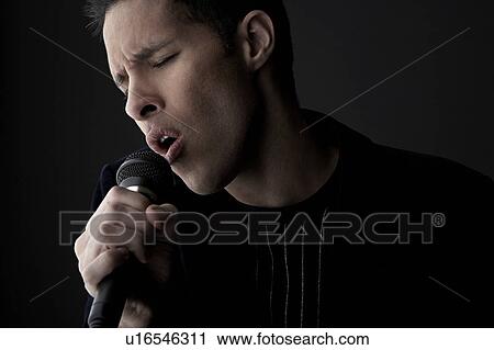 Young man singing into microphone, close-up View Large Photo Image Stock Image - Young man singing into microphone, close-up. Fotosearch