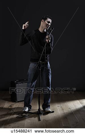 Stock Image - Young man singing on stage. Fotosearch