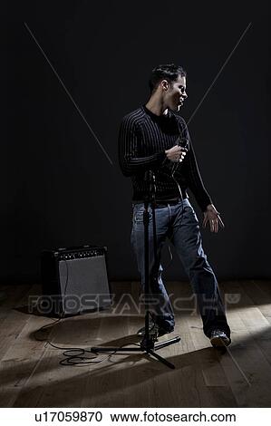 Stock Image - Young man singing on stage. Fotosearch