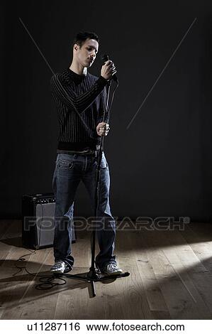 Young man with microphone on stage View Large Photo Image Stock Photograph - Young man with microphone on stage. Fotosearch