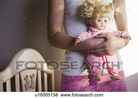 Stock Photo - Young woman holding doll. Fotosearch