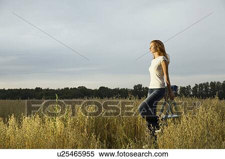 Stock Photography - Young Woman in a Field Standing on a Step Ladder. Fotosearch