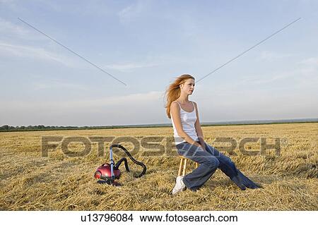 Picture - Young Woman in a Field with a Vacuum Cleaner. Fotosearch