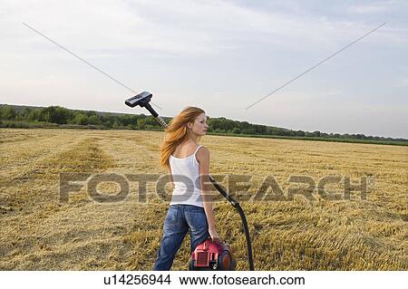 Picture - Young Woman in a Field with a Vacuum Cleaner. Fotosearch