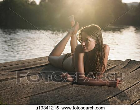 Young woman in bikini lying on jetty, looking away View Large Photo Image Stock Photography - Young woman in bikini lying on jetty, looking away. Fotosearch