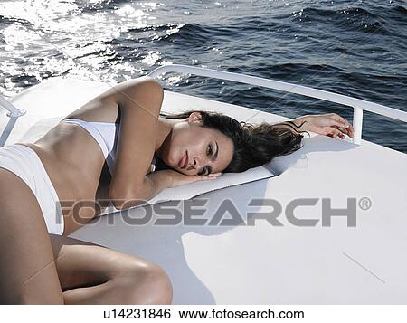 Stock Photograph - Young woman in bikini relaxing on yacht. Fotosearch