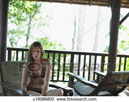 Stock Image - Young Woman in Deck Chair Beneath Veranda. Fotosearch