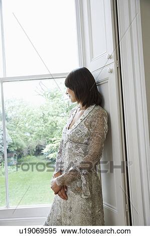 Young woman in romantic dress looking through window View Large Photo Image Stock Photography - Young woman in romantic dress looking through window. Fotosearch