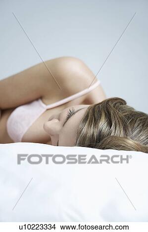 Picture - Young woman in underwear lying on bed, close-up. Fotosearch