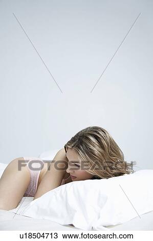 Young woman in underwear lying on bed View Large Photo Image Stock Image - Young woman in underwear lying on bed. Fotosearch