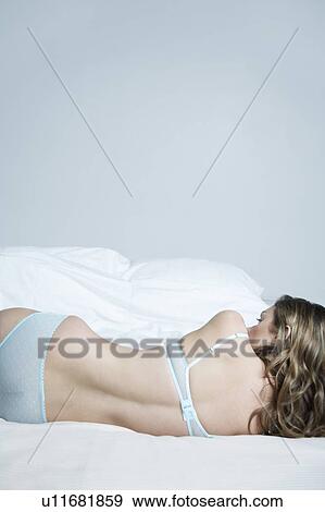 Young woman in underwear lying on bed, back view View Large Photo Image Stock Photo - Young woman in underwear lying on bed, back view. Fotosearch