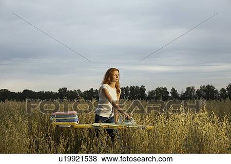 Stock Photo - Young Woman Ironing in a Field. Fotosearch