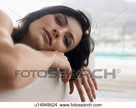 Picture - Young woman leaning head on couch indoors, close-up. Fotosearch