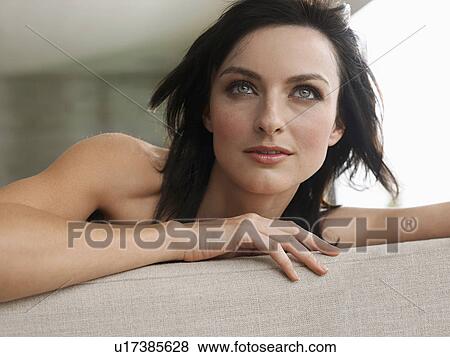 Young woman leaning on couch indoors, close-up View Large Photo Image Stock Photo - Young woman leaning on couch indoors, close-up. Fotosearch
