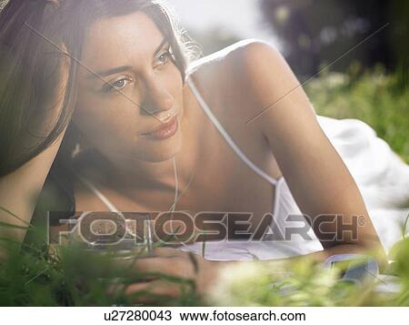 Young woman lying in meadow, leaning on elbow, with drinking glass View Large Photo Image Stock Image - Young woman lying in meadow, leaning on elbow, with drinking glass. Fotosearch