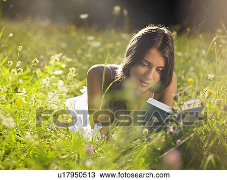 Young woman lying in meadow reading book View Large Photo Image Stock Image - Young woman lying in meadow reading book. Fotosearch