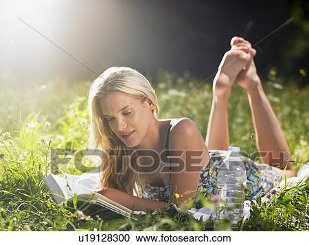 Young woman lying in meadow, reading book View Large Photo Image Stock Image - Young woman lying in meadow, reading book. Fotosearch