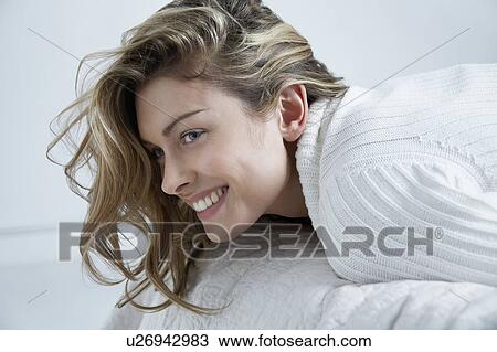 Young woman lying on bed, smiling, close-up View Large Photo Image Stock Image - Young woman lying on bed, smiling, close-up. Fotosearch