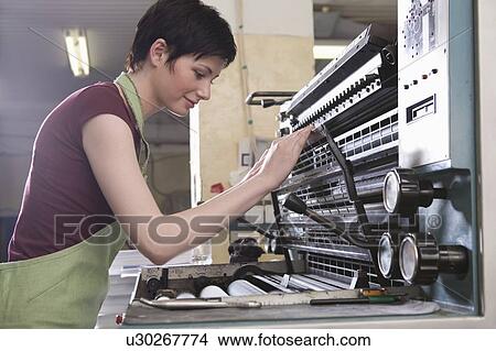 Picture - Young woman operating printing press. Fotosearch