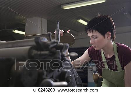 Stock Image - Young woman operating printing press. Fotosearch
