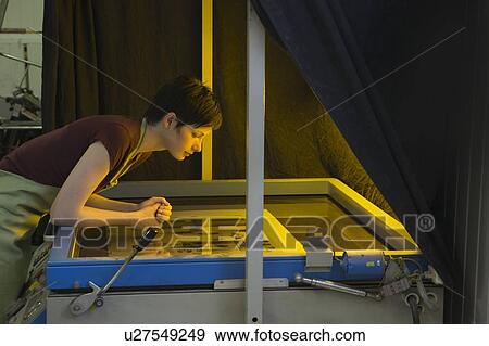 Stock Photo - Young woman operating printing press. Fotosearch