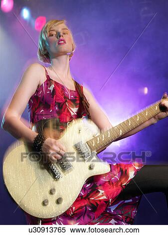Young Woman playing guitar in concert on stage, low angle view View Large Photo Image Stock Photography - Young Woman playing guitar in concert on stage, low angle view. Fotosearch