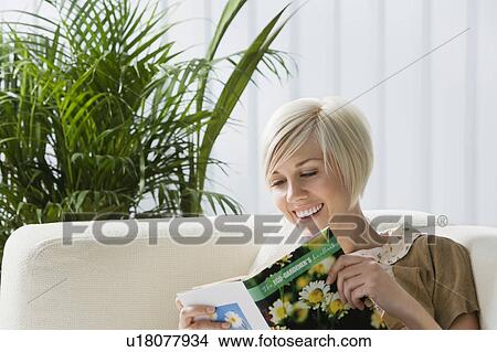 Young woman reading book on sofa View Large Photo Image Picture - Young woman reading book on sofa. Fotosearch