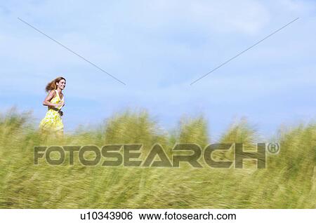 Young Woman Running through Tall Grass in meadow View Large Photo Image Stock Photograph - Young Woman Running through Tall Grass in meadow. Fotosearch